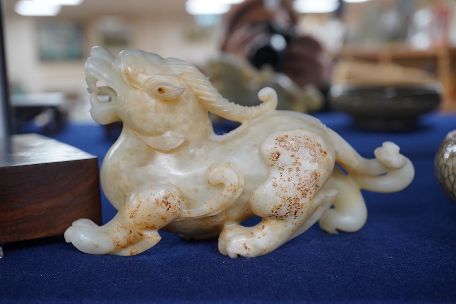 A large Chinese archaistic white jade figure of a mythical beast, hardwood stand, 9cm high, 16cm wide. Condition - good.